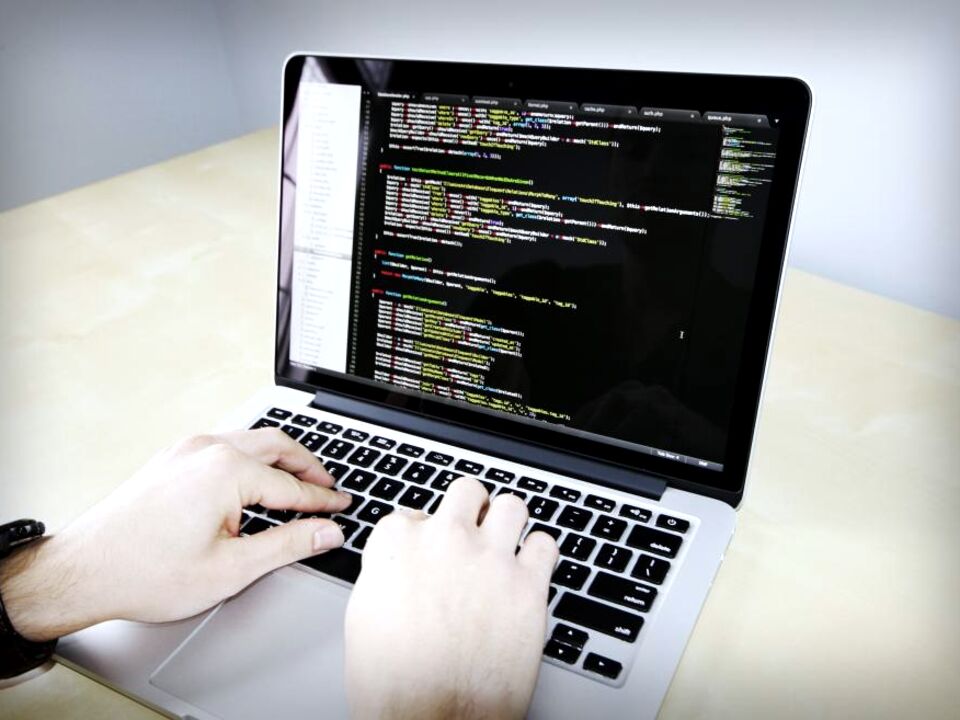 Hands typing code on a laptop