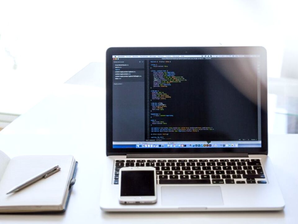 A laptop with code on screen on a tidy desk