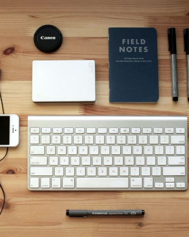 A keyboard and notebook on a wooden desk